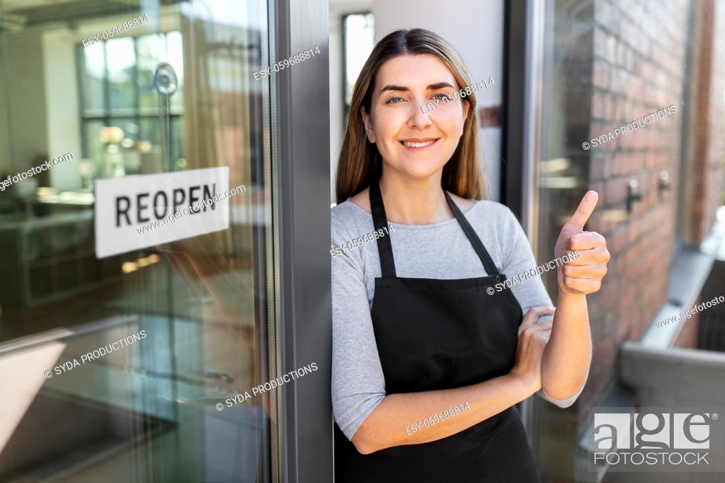 Stock Photo: woman with reopen banner on door showing thumbs up.