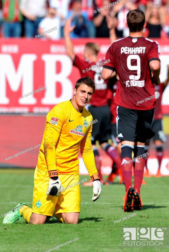 Stock Photo: Bremen's keeper Sebastian Mielitz looks disappointed after the 2-1 goal for Nuremberg, while goal scorer Sebastian Polter (back) cheers during the Bundesliga.