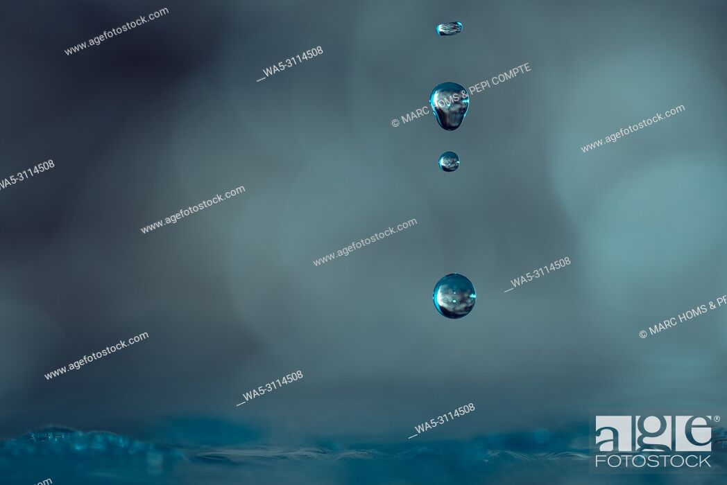 Stock Photo: Drops of water falling towards the surface blue color.