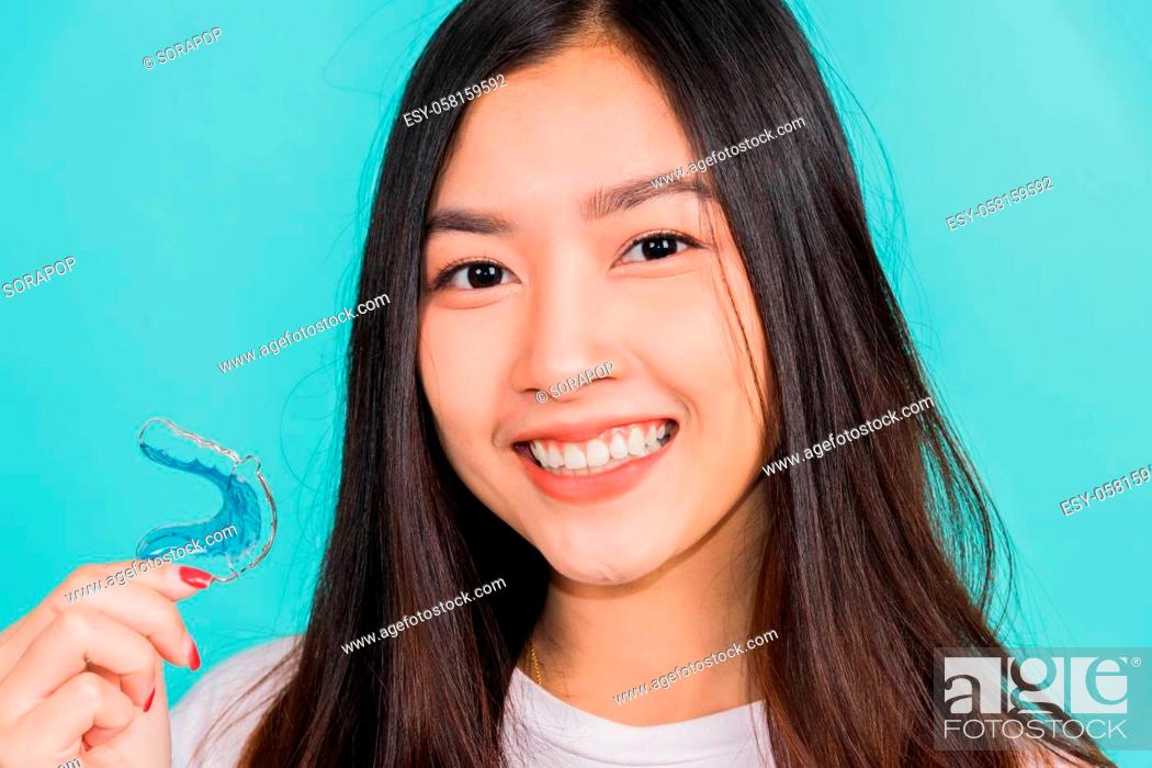 Stock Photo: Portrait young Asian beautiful woman smiling holding silicone orthodontic retainers for teeth, Teeth retaining tools after removable braces.