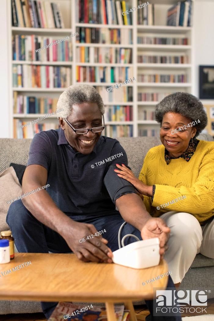 Imagen: Senior couple checking blood pressure in living room.