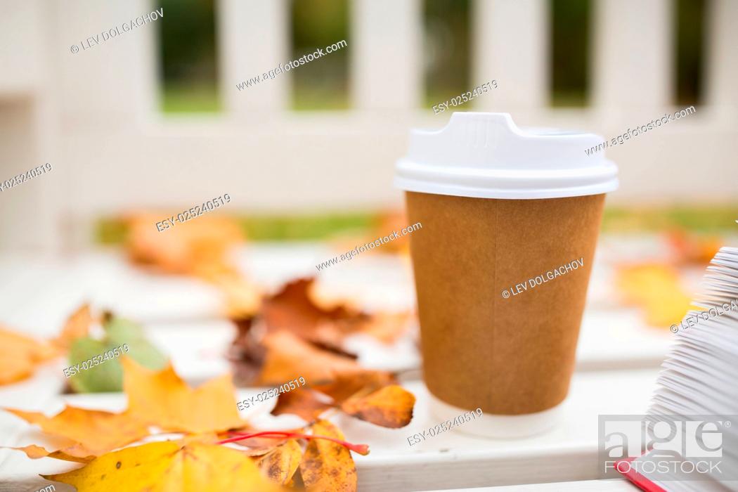 Stock Photo: season, advertisement and drinks concept - coffee in paper cup on bench in autumn park.