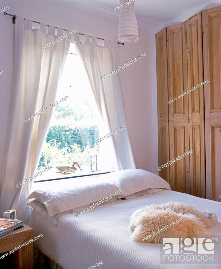 Stock Photo: Bded in front of window with white curtains.