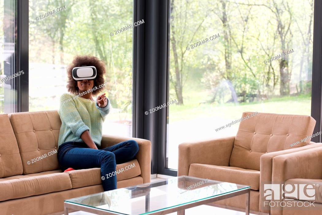 Stock Photo: Happy african american girl getting experience using VR headset glasses of virtual reality at home.