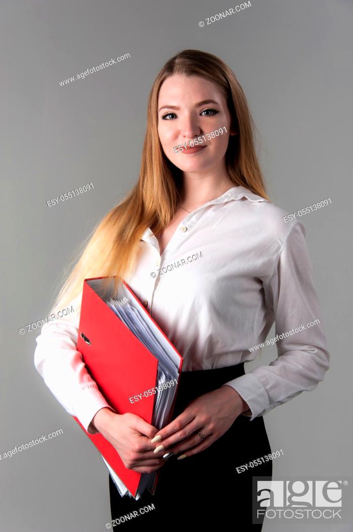 Stock Photo: Portrait of a young attractive woman with blond hair on a neutral gray background. Red folder in hand.