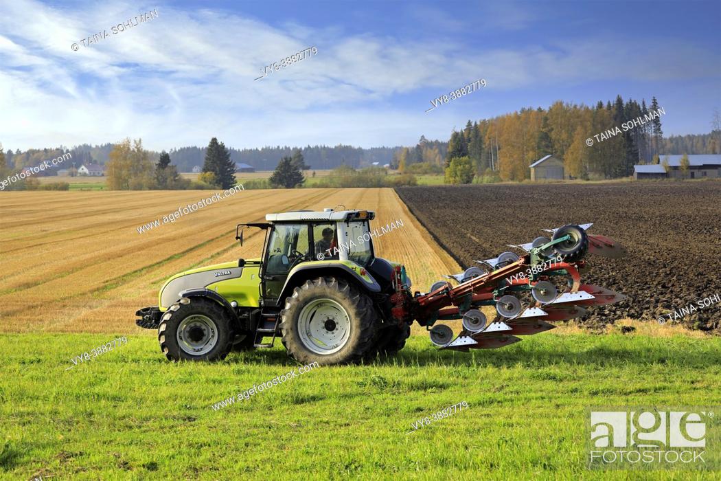 Stock Photo: Farmer plowing field with green Valtra tractor and plough on a sunny autumn afternoon in South of Finland. Jokioinen, Finland. October 2, 2020.