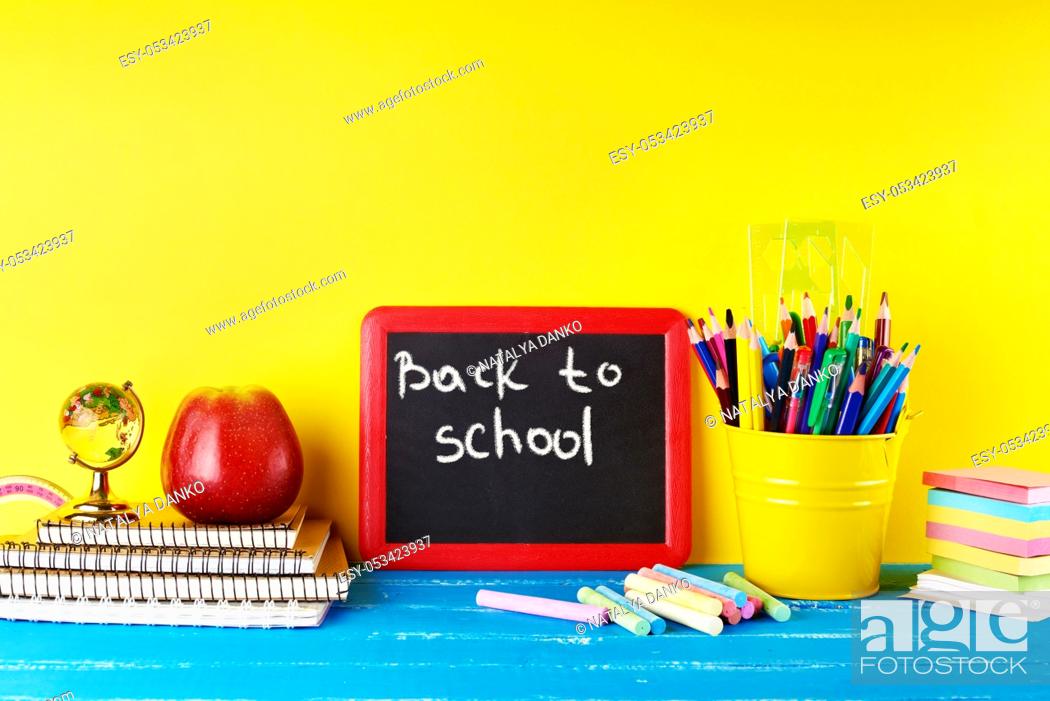 Imagen: black chalk frame, chalks and school supplies on a blue background, concept back to school.