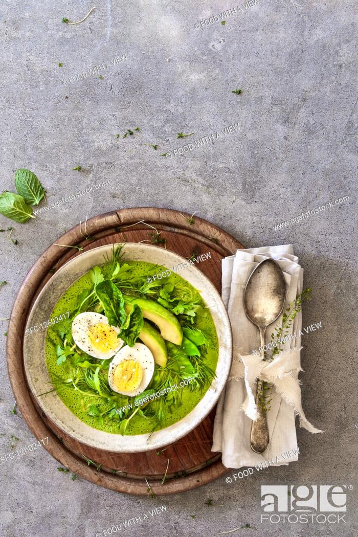 Stock Photo: A smoothie bowl with boiled egg, avocado and mange tout in a nest of herbs.