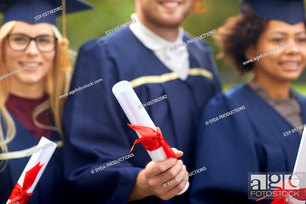 Stock Photo: graduate students in mortar boards with diplomas.