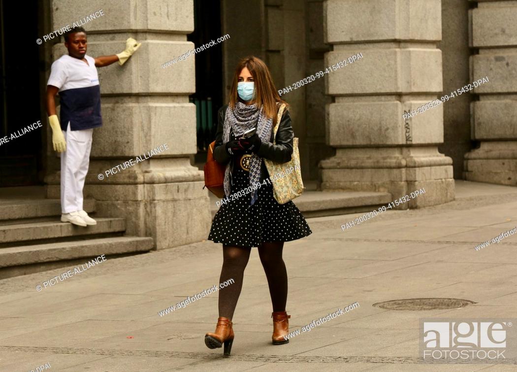 Stock Photo: 20 March 2020, Spain, Madrid: A woman wearing a mouthguard walks across the Plaza del Sol during a curfew imposed because of the coronavirus.