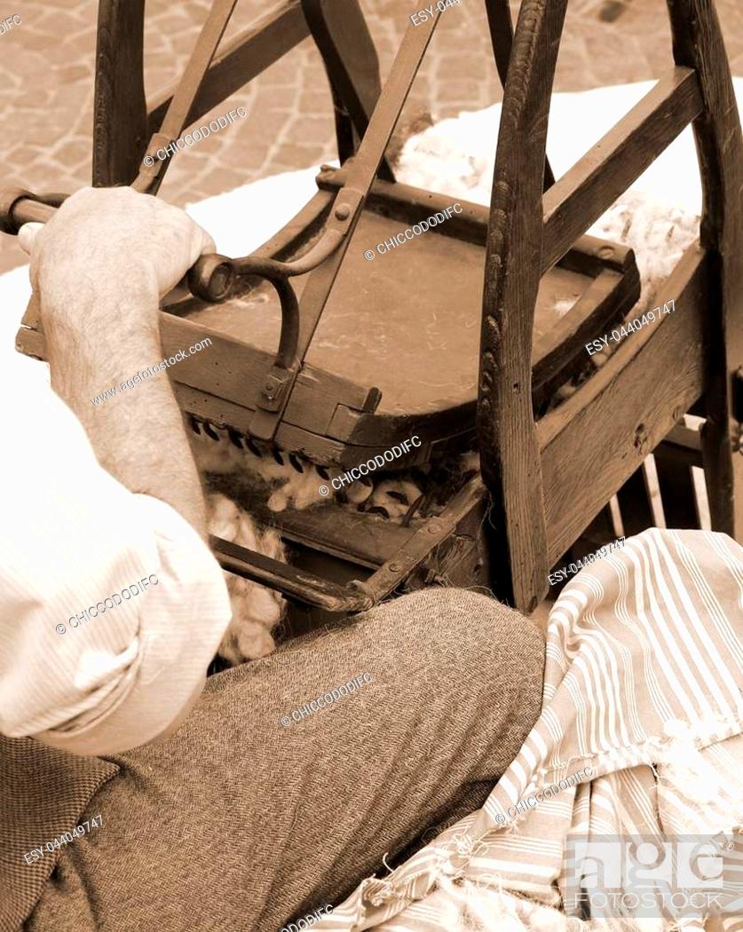 Stock Photo: Senior carder man while carding wool or cotton with old wooden machine.