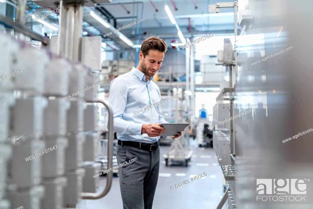 Stock Photo: Businessman using tablet in a modern factory.