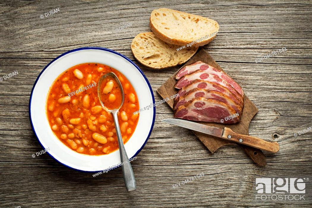 Stock Photo: White bean stew with tomato sauce and meat on wooden table.