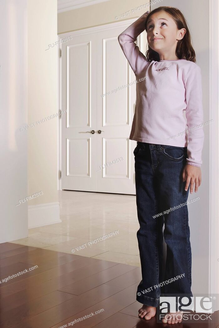 Stock Photo: Young Girl Measuring her Height against a Door Frame, Toronto, Ontario.