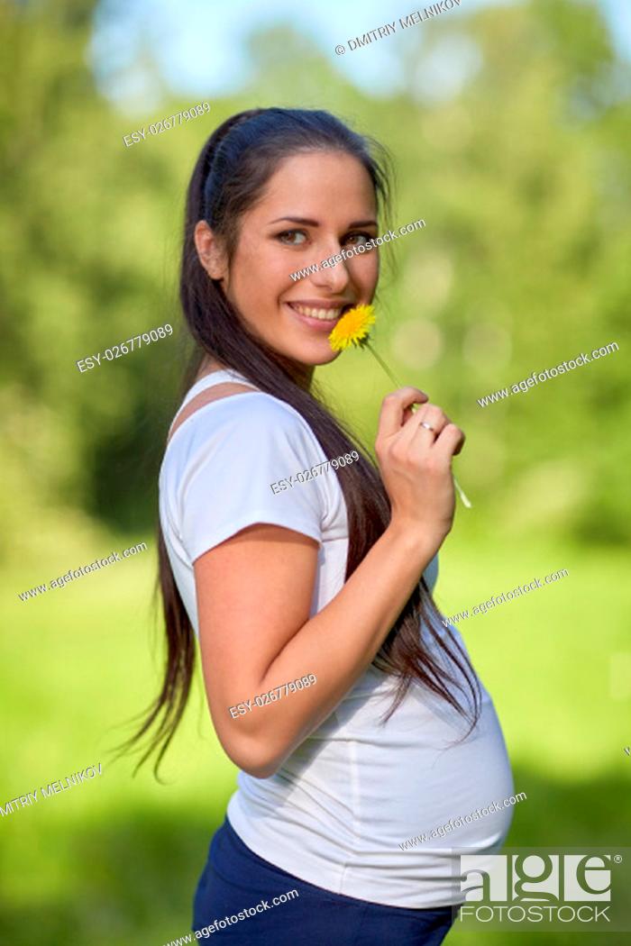Stock Photo: Young pregnant woman with flower in the summer park.
