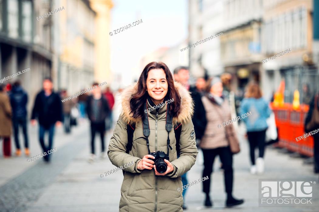 Stock Photo: portrait Beautiful young tourist woman stands in the background of a crowd of people on a central street in Munich in Germany in winter.