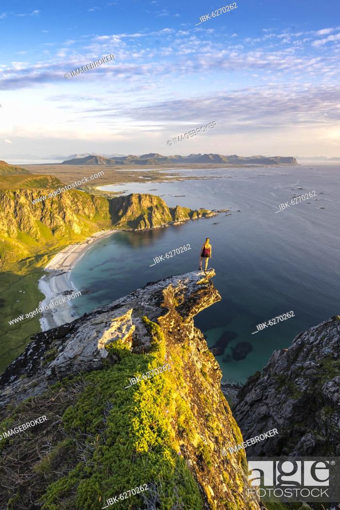 Stock Photo: Evening atmosphere, hiker standing on a cliff, view to rocks, beach and sea, top of the mountain Måtinden, near Stave, Nordland, Norway, Europe.