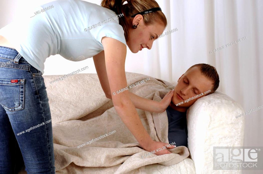Stock Photo: Young woman carpets her sleeping boyfriend on a sofa. - 30/06/2008.