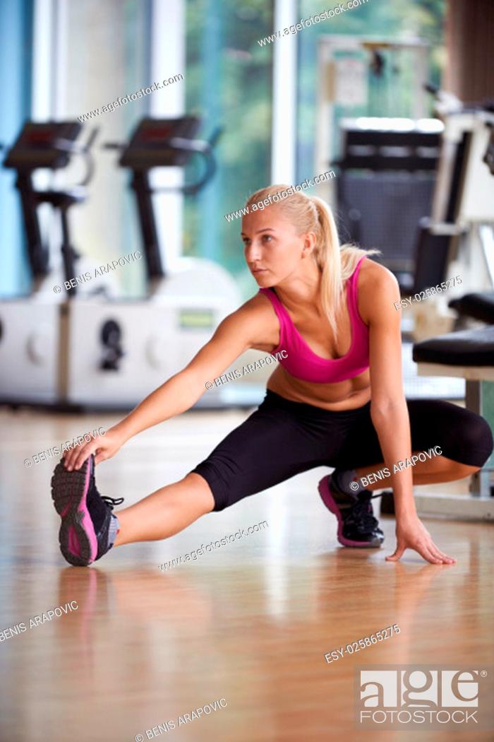 Stock Photo: Cute young woman stretching and warming up for her training at a gym.