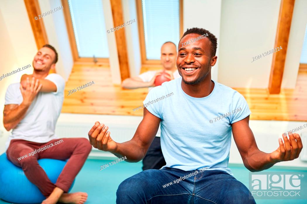 Photo de stock: Afrikanischer Mann in einem Wellness Kurs macht eine Yoga Übung für die innere Ruhe.