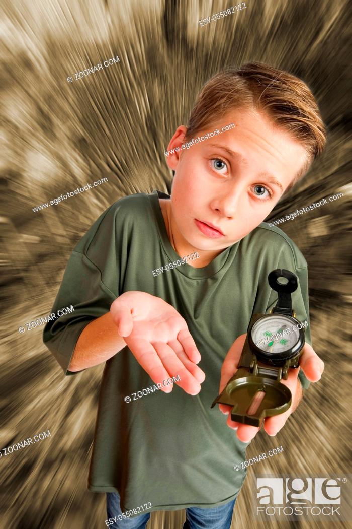 Stock Photo: Image of a 12-year-old Caucasian boy in an elevated, wide-angle three-quarter view with a compass on his left hand, looking at the camera helplessly against a.