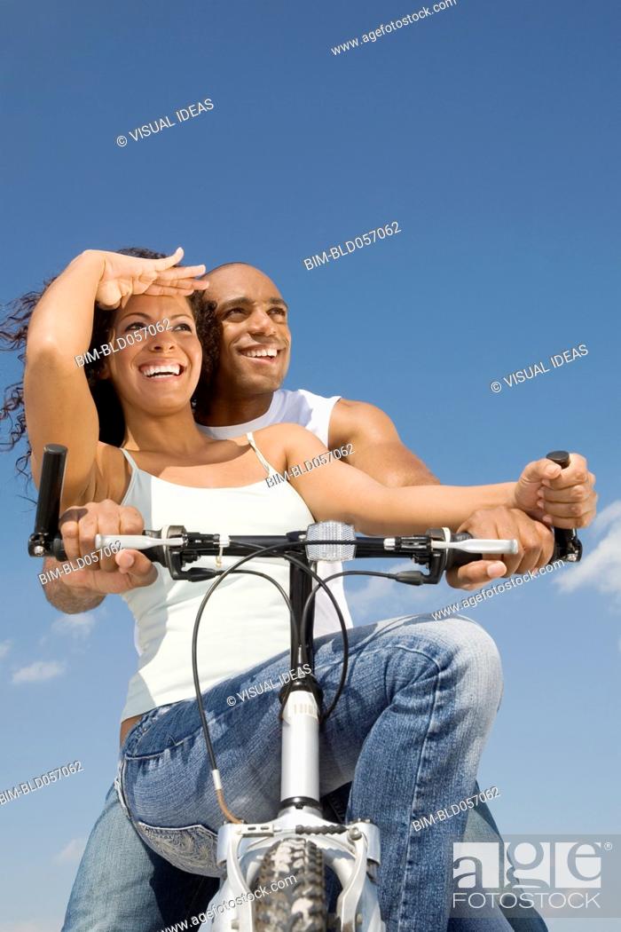 Stock Photo: Multi-ethnic couple sitting on bicycle.