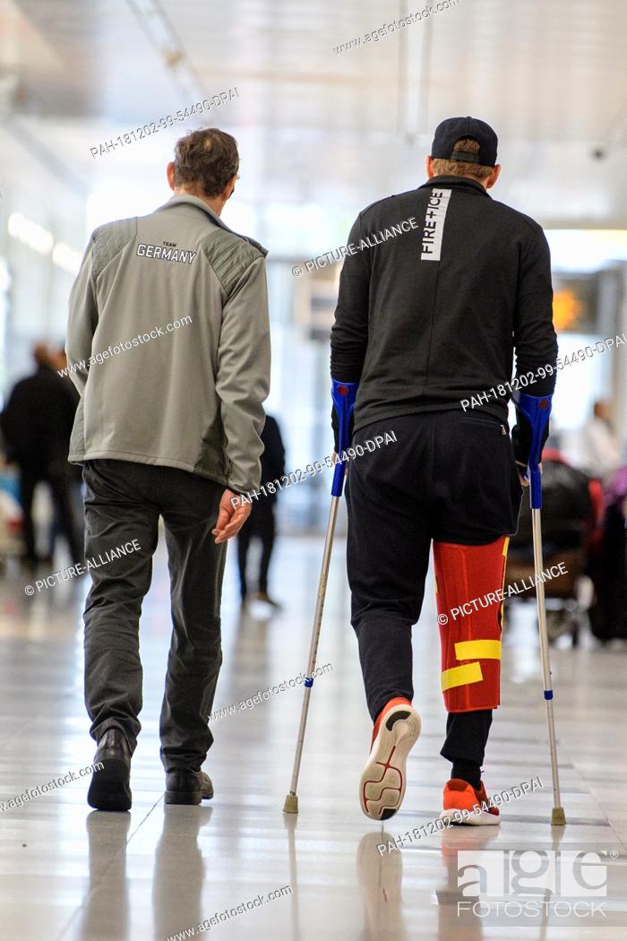 Stock Photo: 02 December 2018, Bavaria, München: Ski racer Thomas Dreßen (r) arrives at the airport in Beaver Creek after his heavy fall on the descent.