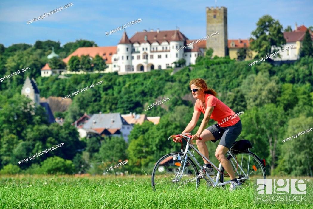 Stock Photo: Woman cycling, Neubeuern castle in background, Neubeuern, Upper Bavaria, Bavaria, Germany.