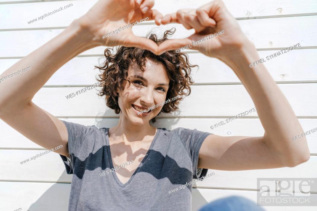 Stock Photo: Happy woman shaping heart with her hands.