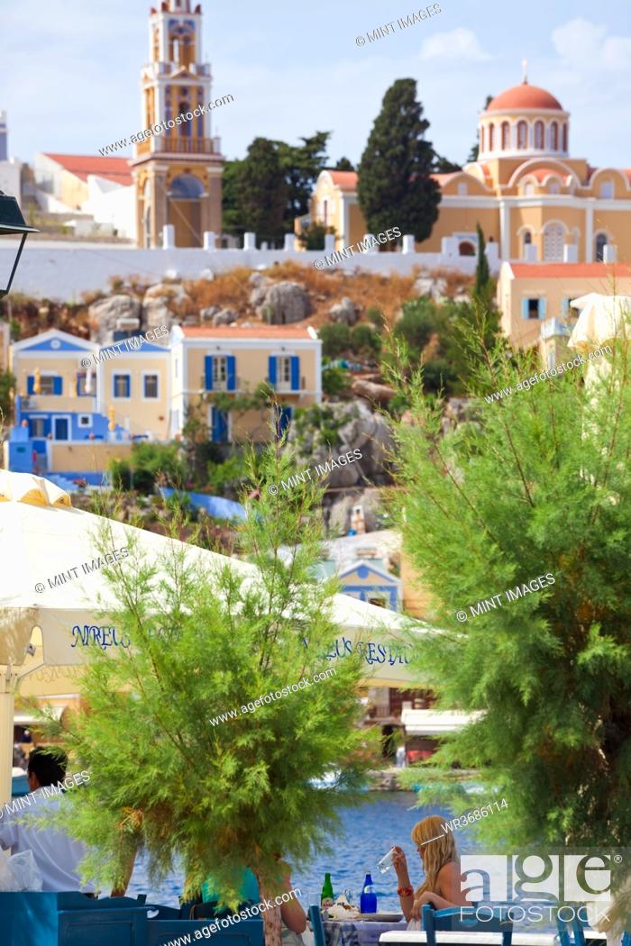 Stock Photo: Symi Town, elevated view, rooftops, terraces, restaurant, people in the background.