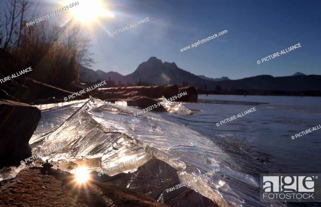 Stock Photo: 15 February 2023, Bavaria, Füssen: Ice thaws in the sunshine on the shore of the Hopfensee lake on the edge of the Alps. Photo: Karl-Josef Hildenbrand/dpa.