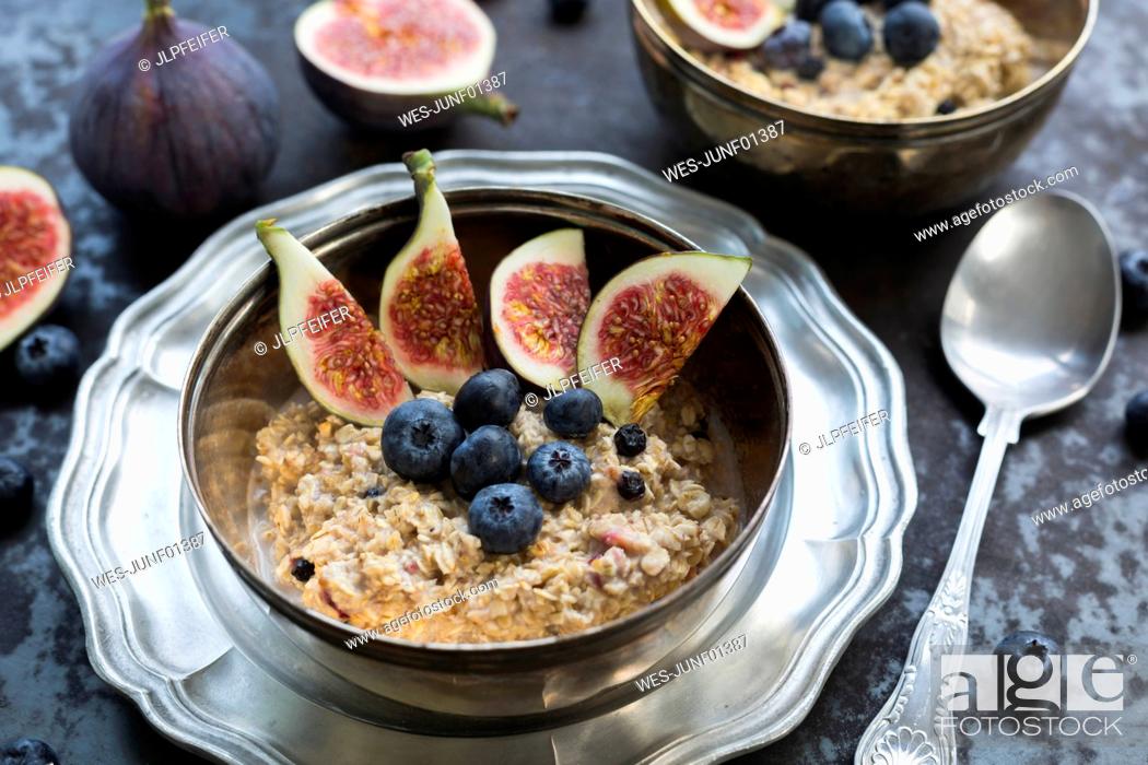 Stock Photo: Bowl of porridge with sliced fig, blueberries and dried berries.